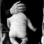 A woman holds a doll's head.