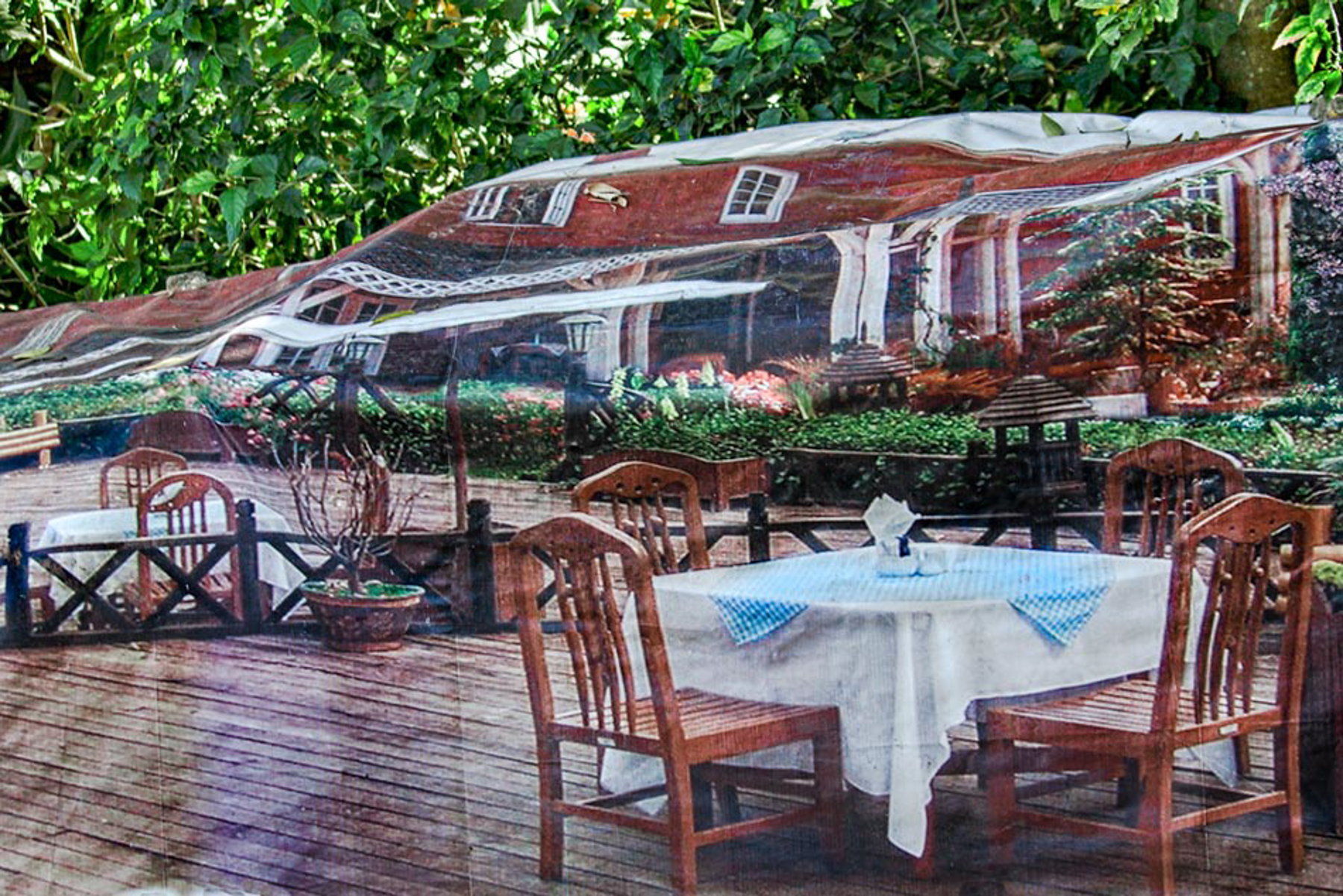 A mural of a house in the background with a table set with chairs.