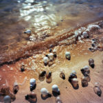 Light bulbs on sand by water.