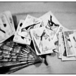 The backs of playing cards with birds and a fan on the table still life.