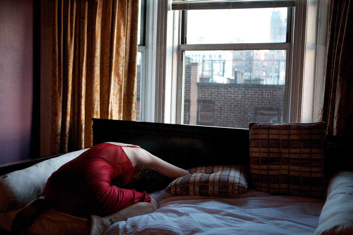 A woman lies on her knees on her bed.