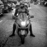 A man in a superhero costume is stopped on a motorcycle.