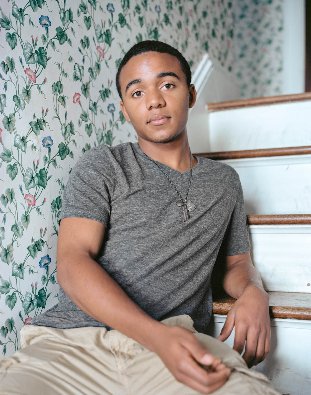 Kevin, a boy seated on stairs in home.