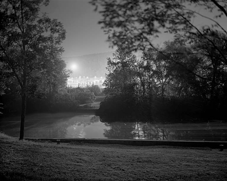 A landscape of a prison at night with lights illuminating it.