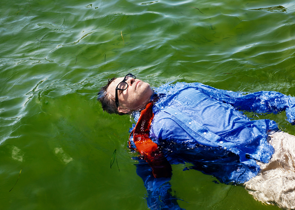 A man in a blue jacket floats in ocean