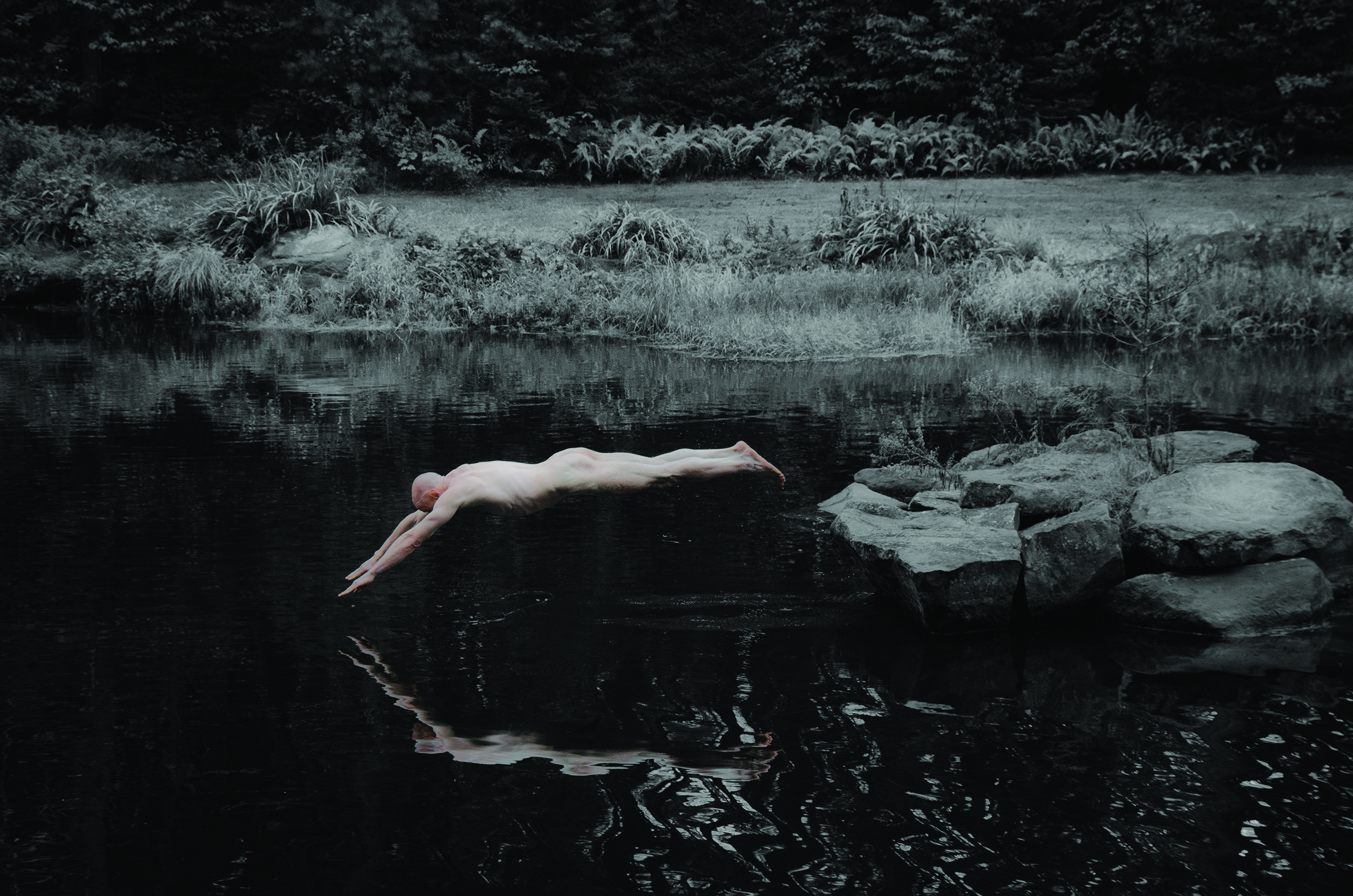 Naked man diving into water