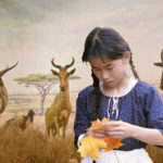 Young girl holding yellow leaves with background of animals