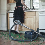 Woman doing the dishes with a vacuum in the foreground..