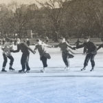 Six people skating on a frozen pond.