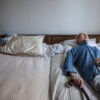 Old man with a cane lying on a bed