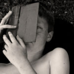 Boy with book in front of his face