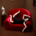 Woman on red couch with limbs akimbo