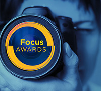 A woman looking through a lens. It is the Focus Logo