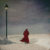 Figure in red coat walking by a lamppost in winter