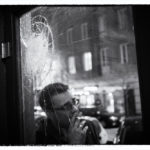 Man leaning against a cracked window