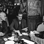 The men around a table in a bar play cards.