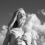 Woman eating cotton candy with clouds that look like cotton candy