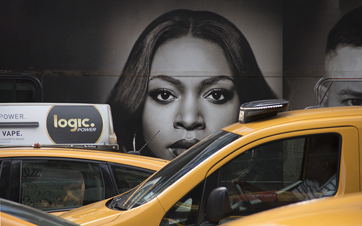 A cab driver passes a large wall mural of a women