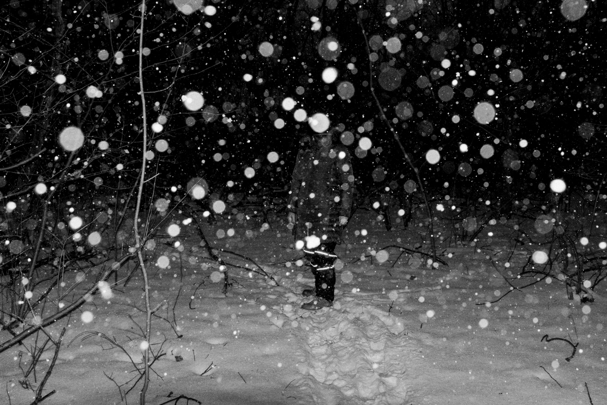 A figure is not recognizable in the woods. It is snowing. © Virgil DiBiase, "When you look at me and question me I go blind.”