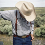A man in a cowboy hat looking downwards.