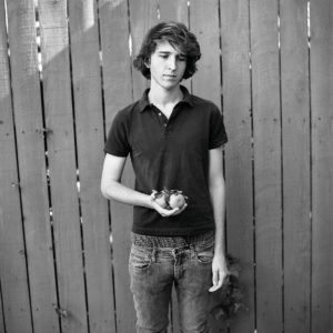 a boy standing in front of a fence