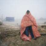 Man in blanket with teepee in background