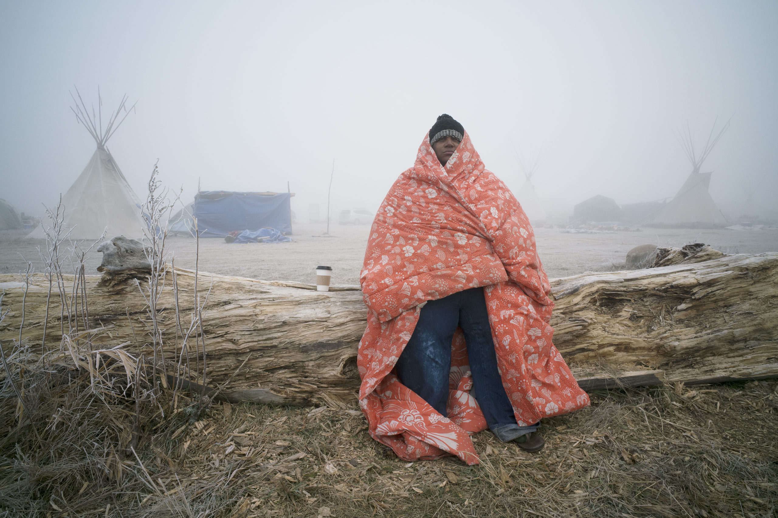 Man in blanket with teepee in background