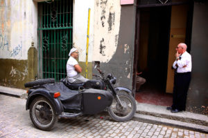 Two men talking, one of motor tricycle