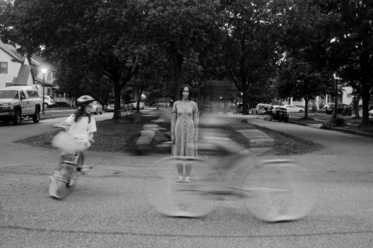 two bicyclists and woman standing